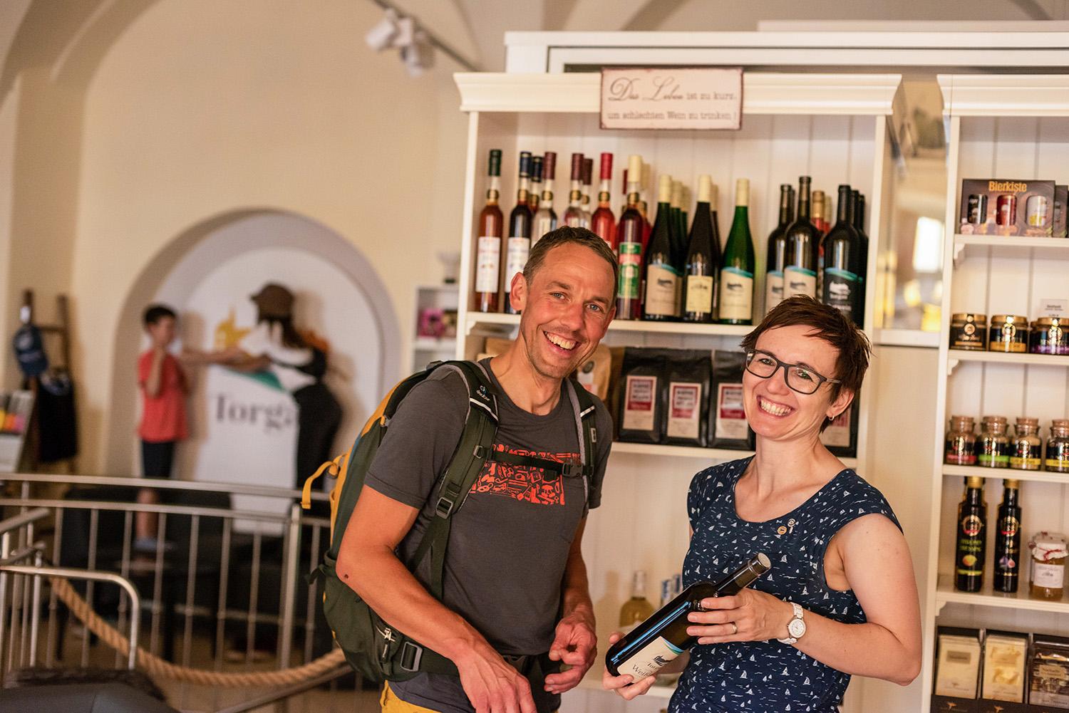 Paar steht vor Regalen des regionalen Shops und hält eine Weinflasche in der Hand