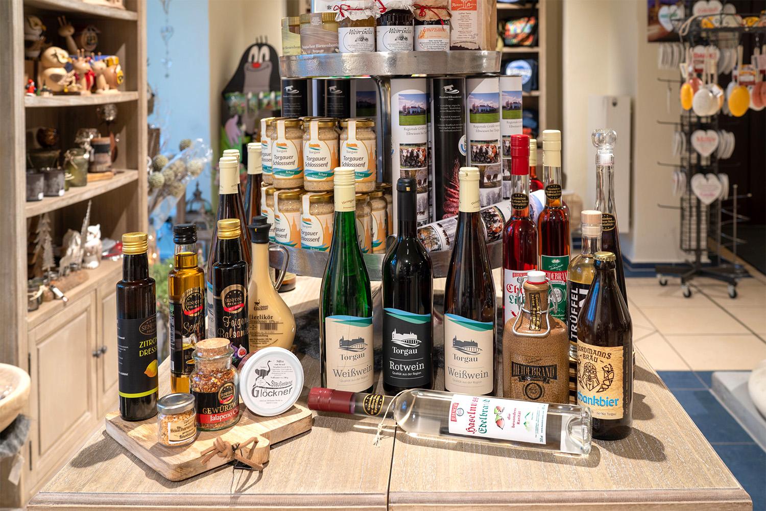 Produktzusammenstellung aus dem großen Sortiment des Torgau Shops mit unter anderem Wein, Öl, Likör, Seife, Salami, Senf, Gewürzen, Kaffee