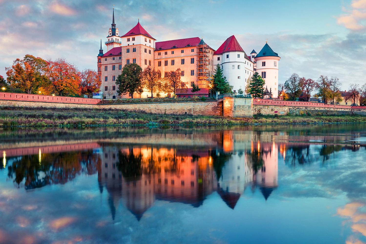 Bilck auf den angeleuchtete Schloss Hartenfels mit der Elbe im Vordergrund