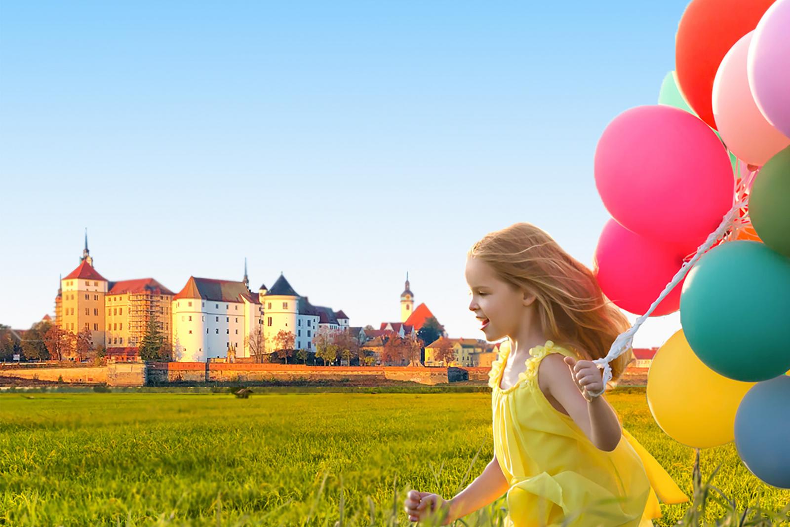 Kind mit bunten Luftballons auf Elbwiesen